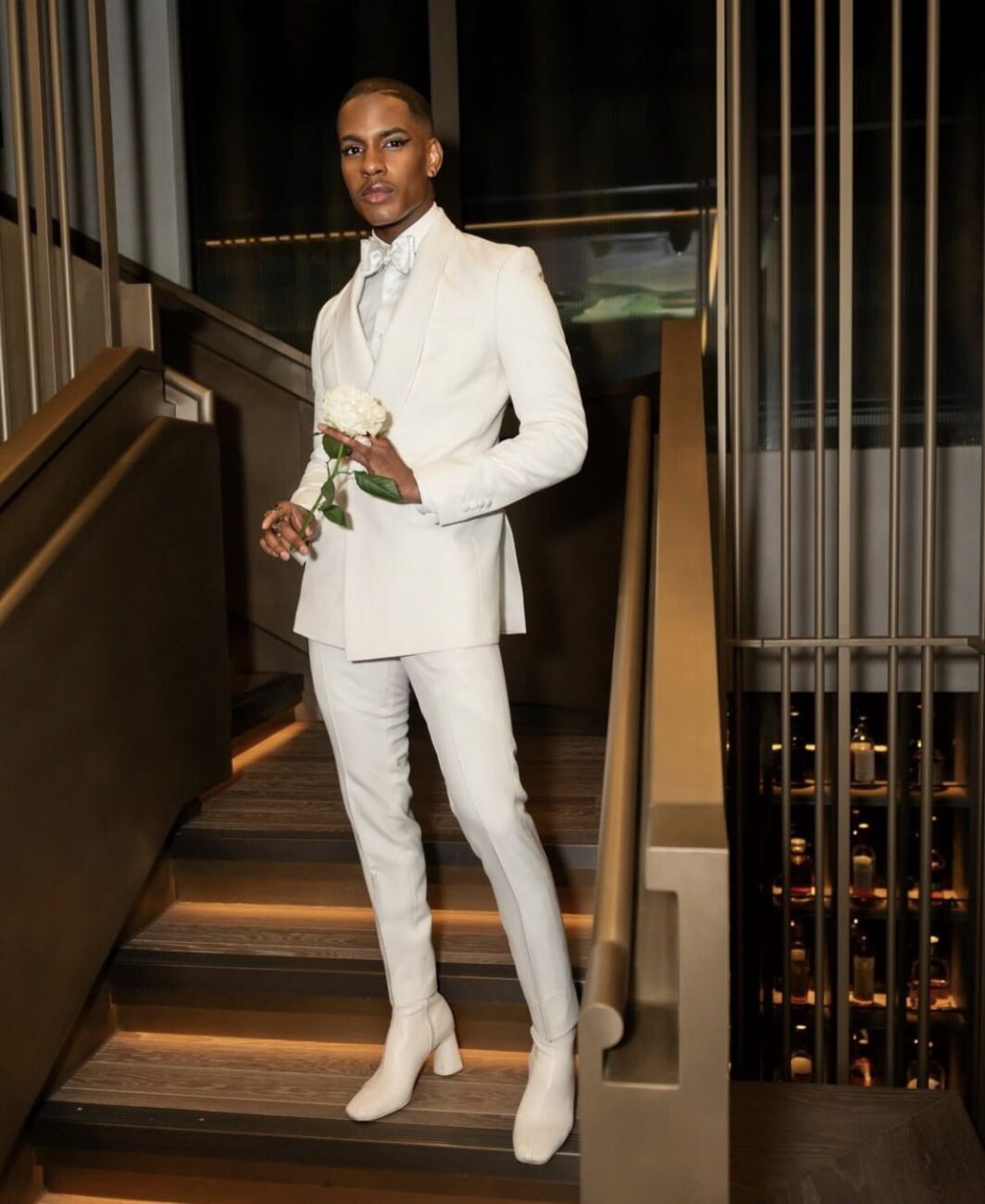 Denola Grey making a bold statement in a form-fitting white two-piece suit and heeled boots.