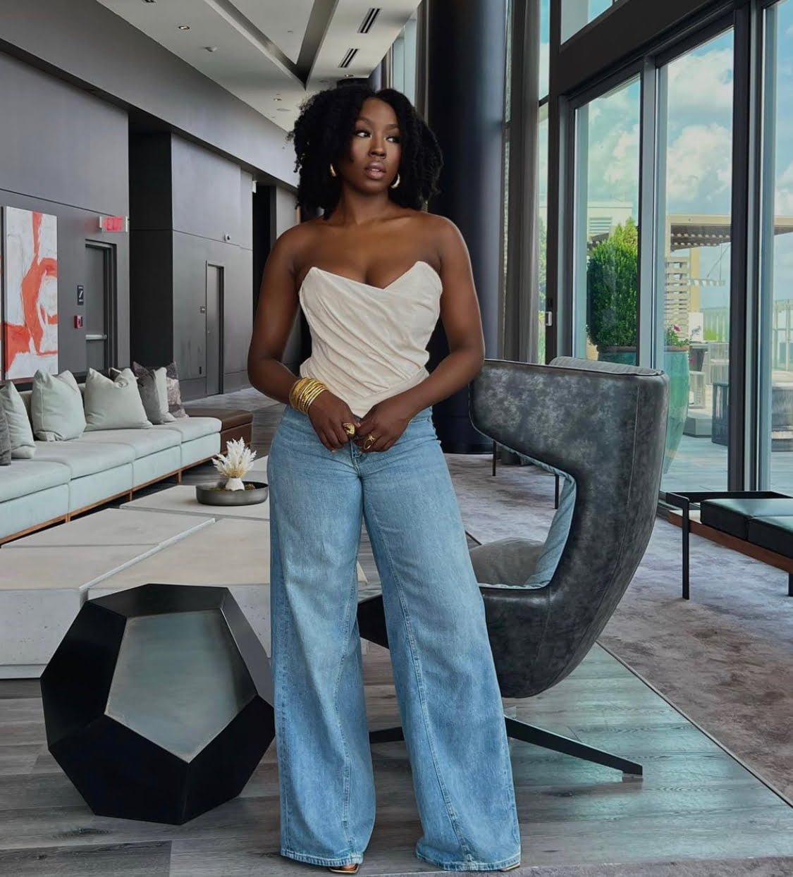 Pro at styling denim: Beverly Naya exudes class in a sleeveless white top, wide-legged jean trousers, and a captivating look.