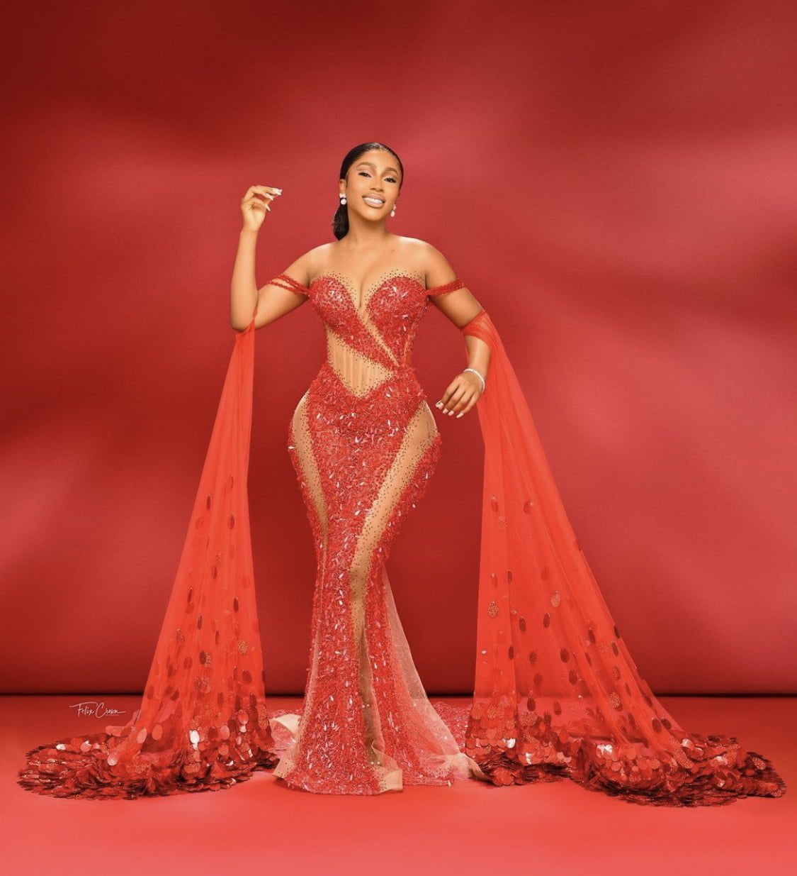 Mercy Eke stuns in red dress with dramatic sleeves.