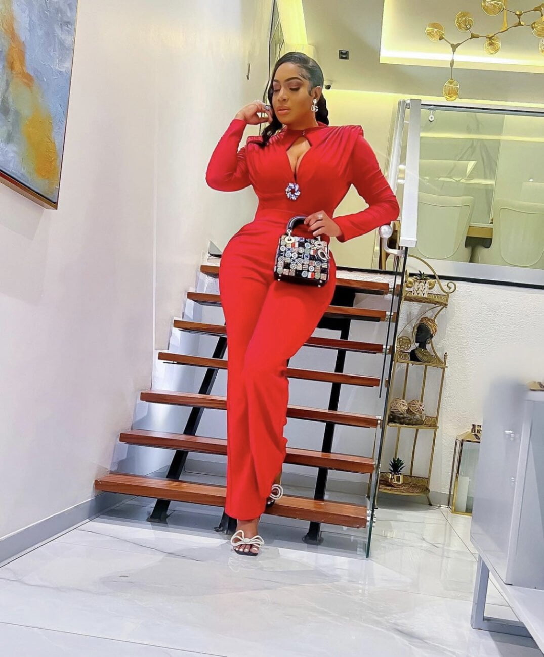 Chika Ike in a red jumpsuit with a shoulder pad and a brooch. 