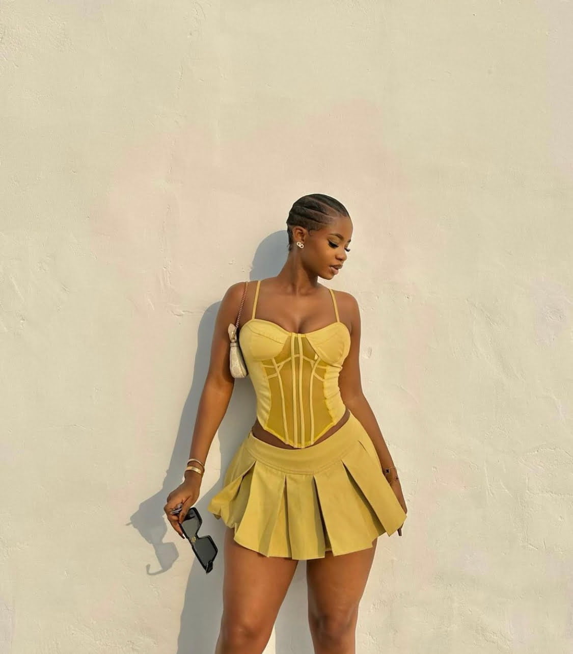 Priscilla Ojo in a show stopping two piece outfit that consists of a corset top and a pleated skirt.