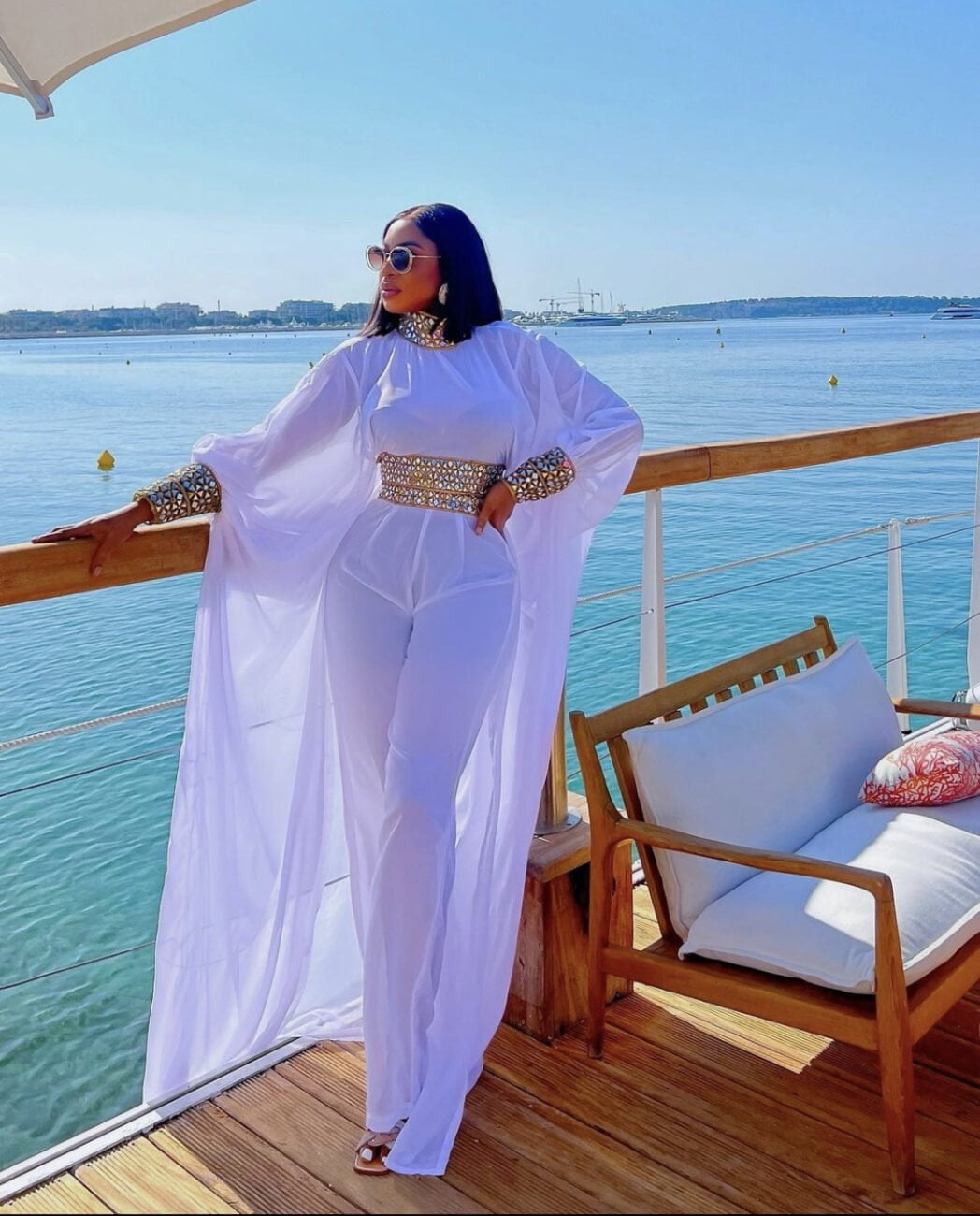 Chika Ike in a bedazzled white jumpsuit that has a cape.