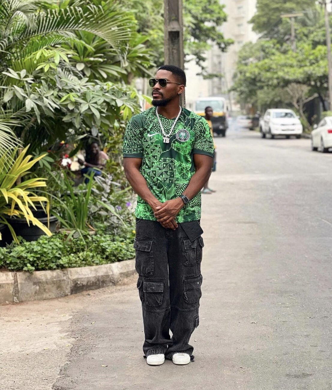 Tobi Bakre in a dark green Nigerian jersey, paired with combat trousers and white sneakers.