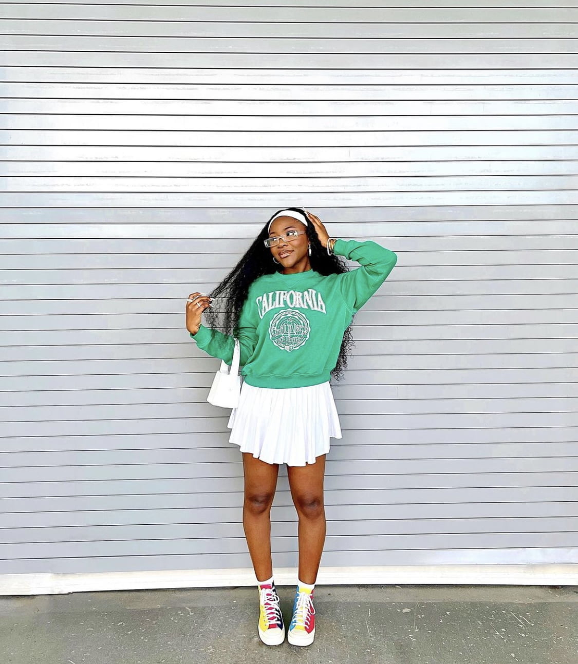 Korean high school fashion inspiration: Green sweater paired with a white pleated skirt, sneakers, and a white headband.