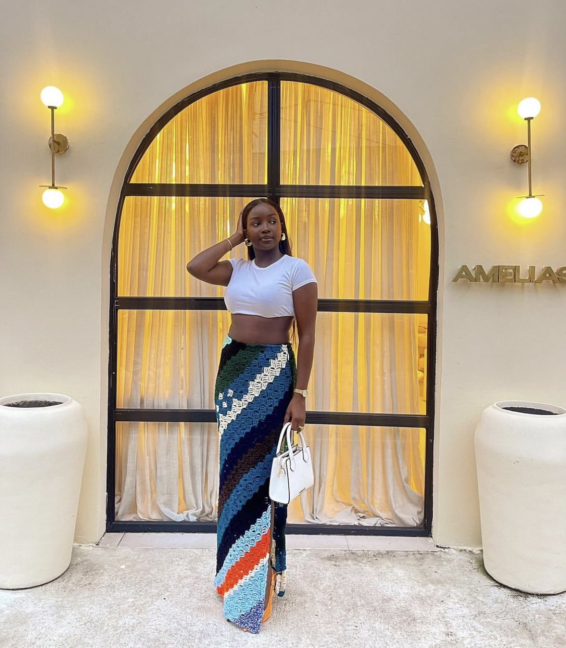 Saskay in a white crop top, paired with a knitted maxi skirt.