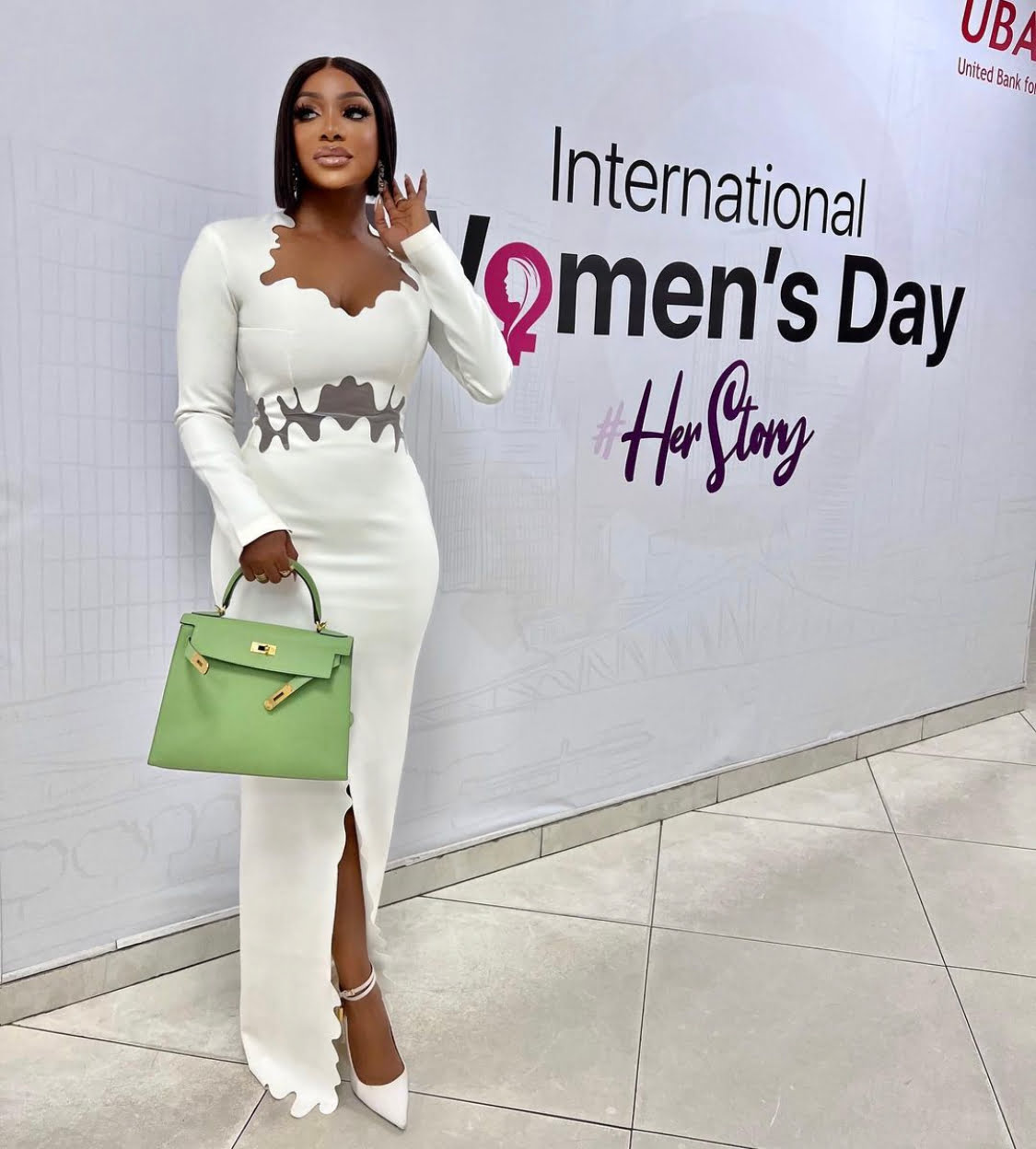 Chioma Good Hair in a white dress with a modest slit.