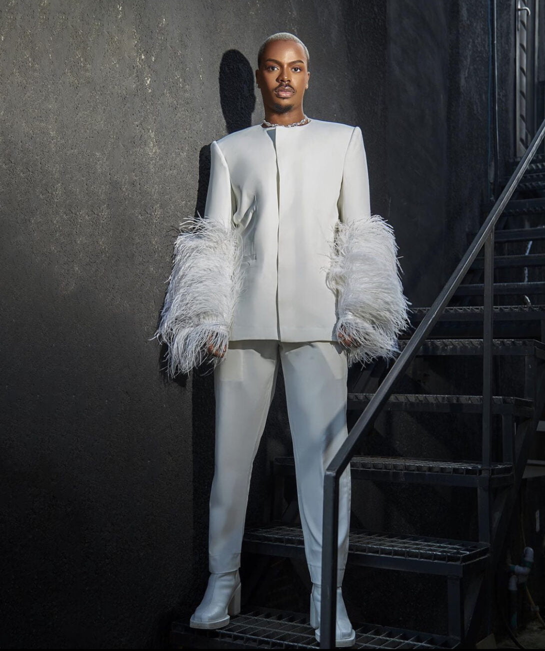 Enioluwa Adeoluwa in a dystopian society inspired white suit with feathers on the sleeves. 