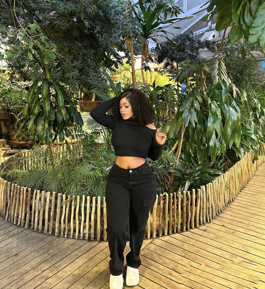 Black crop top, paired with black trousers, and white sneakers.