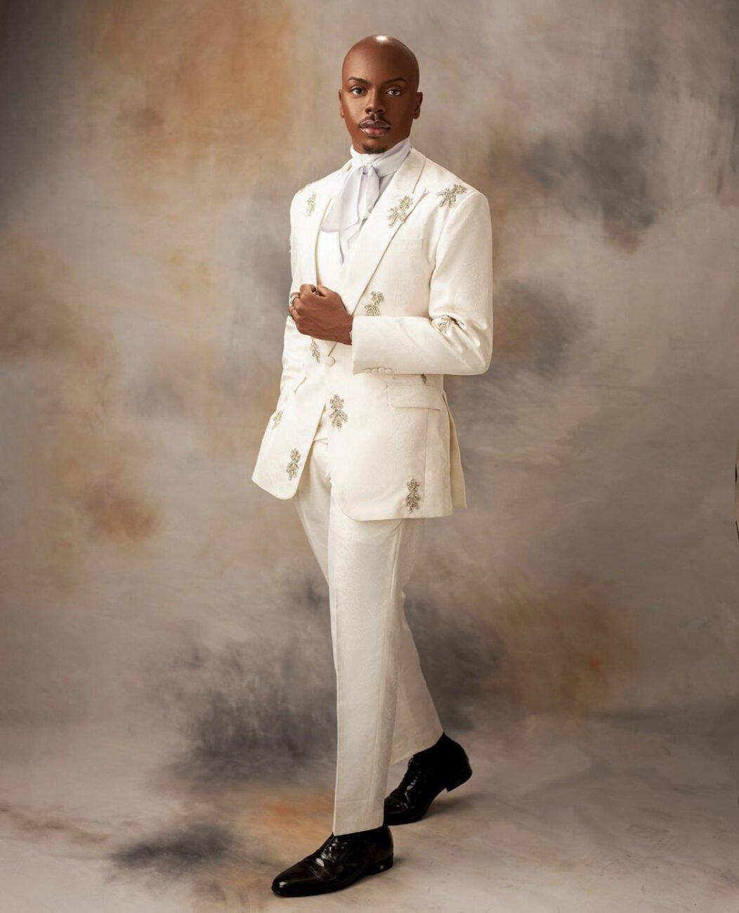 Enioluwa Adeoluwa in a classy white suit with embroidery designs on the jacket.