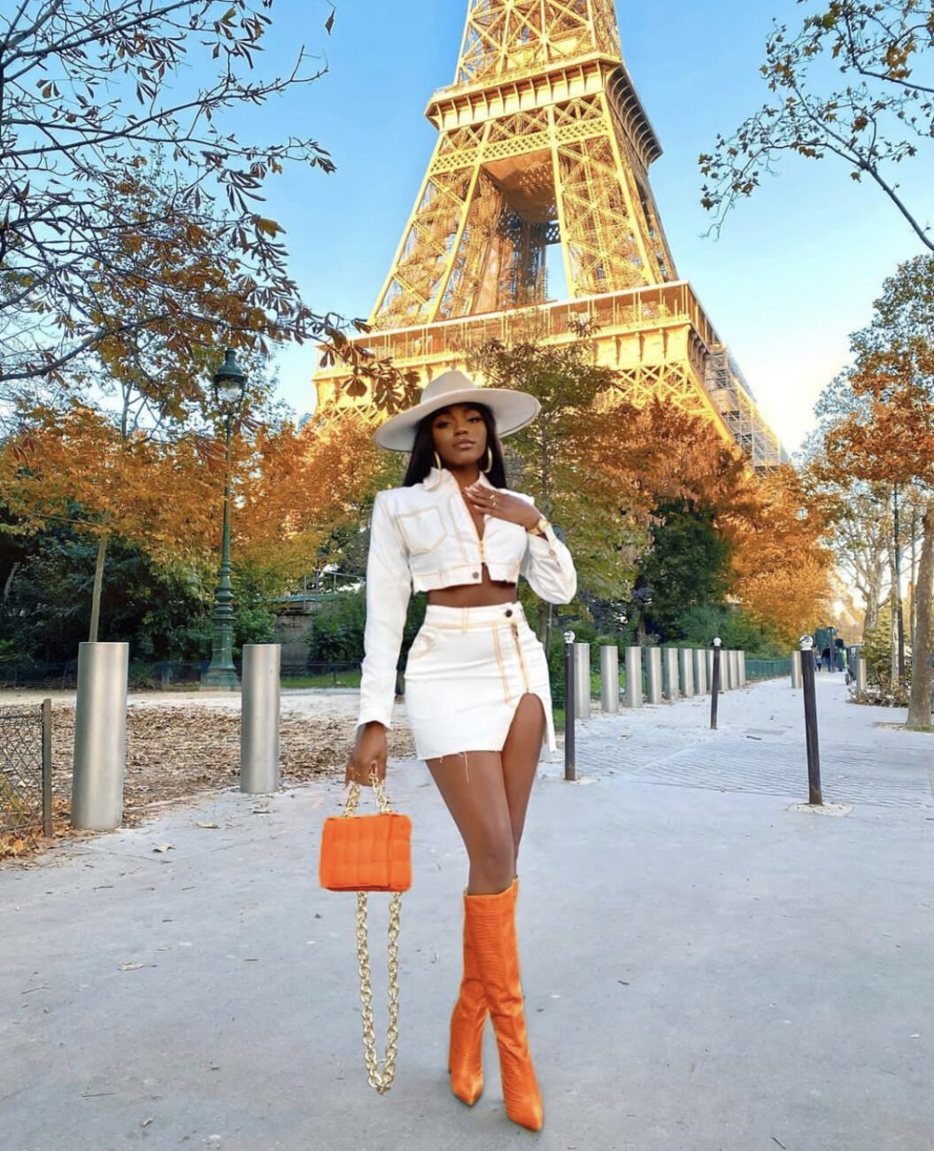 White denim two piece paired with orange colored boots and an orange colored handbag.