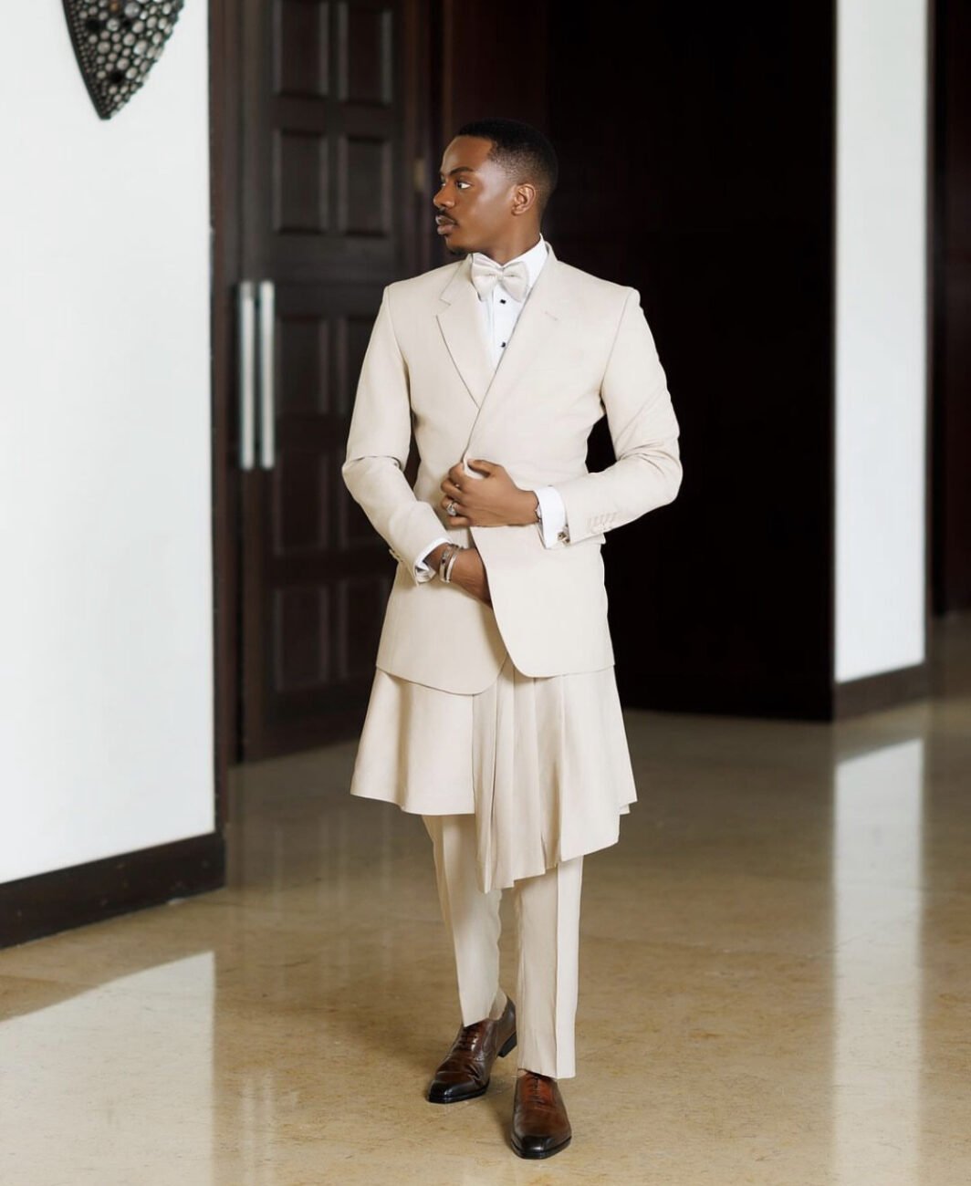 Enioluwa Adeoluwa in a milk colored suit with a skirt paired with the trousers.