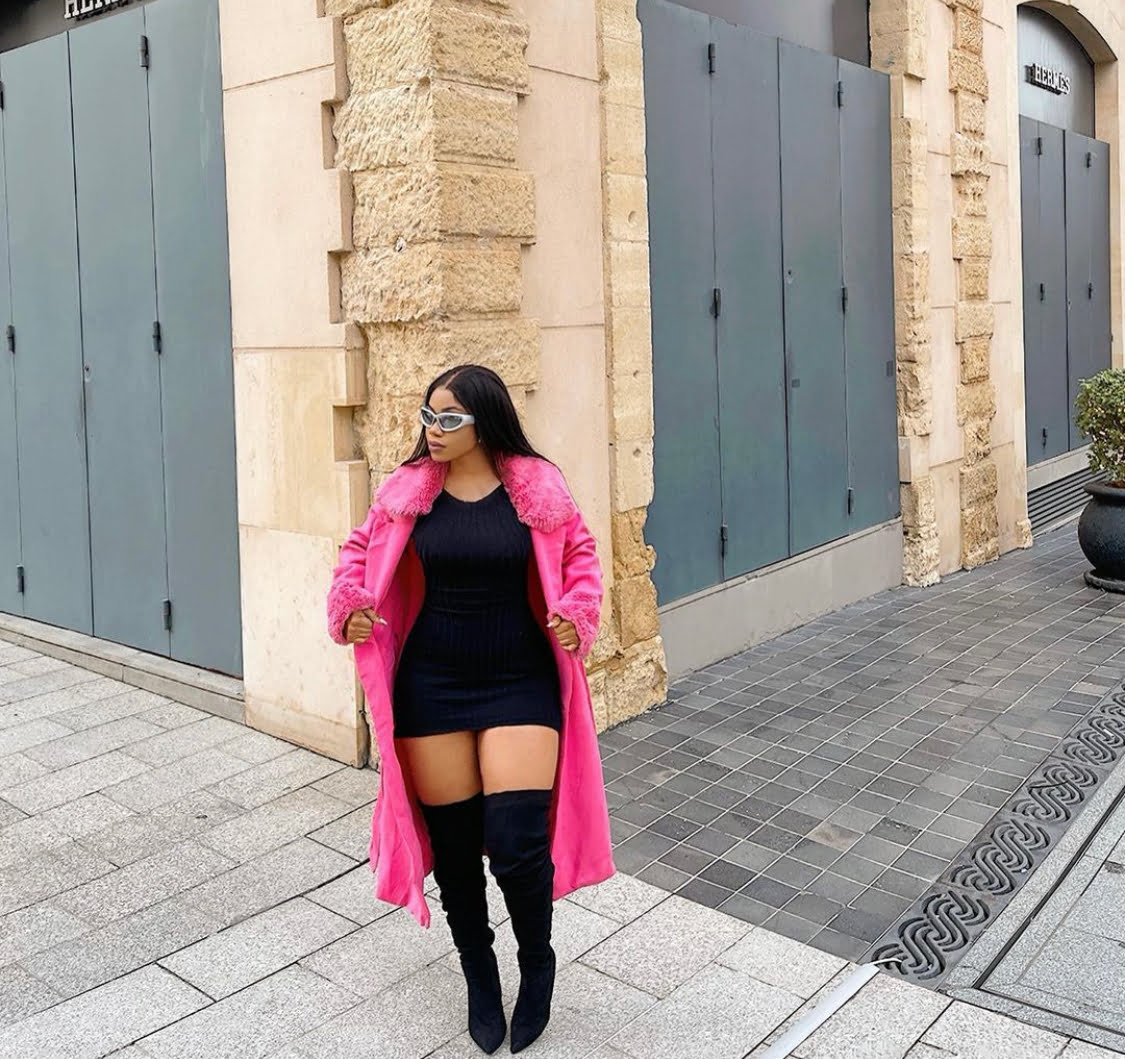 Pink jacket with faux fur neckline and sleeves, paired with a mini black dress and black boots.
