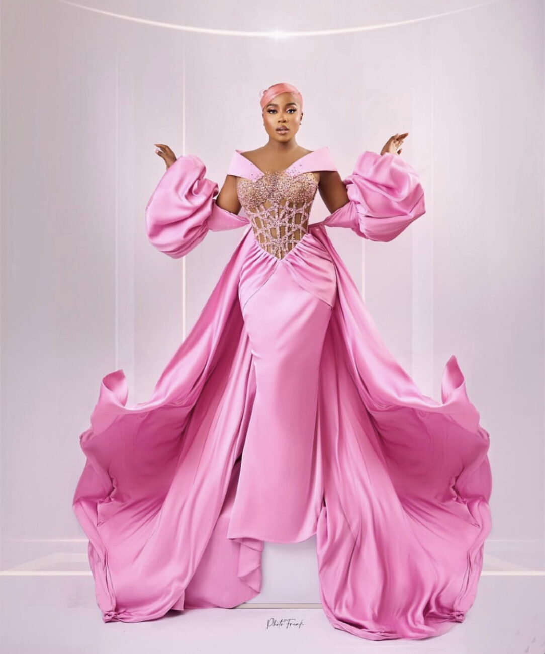 Veekee James in a dramatic pink dress with a cape.
