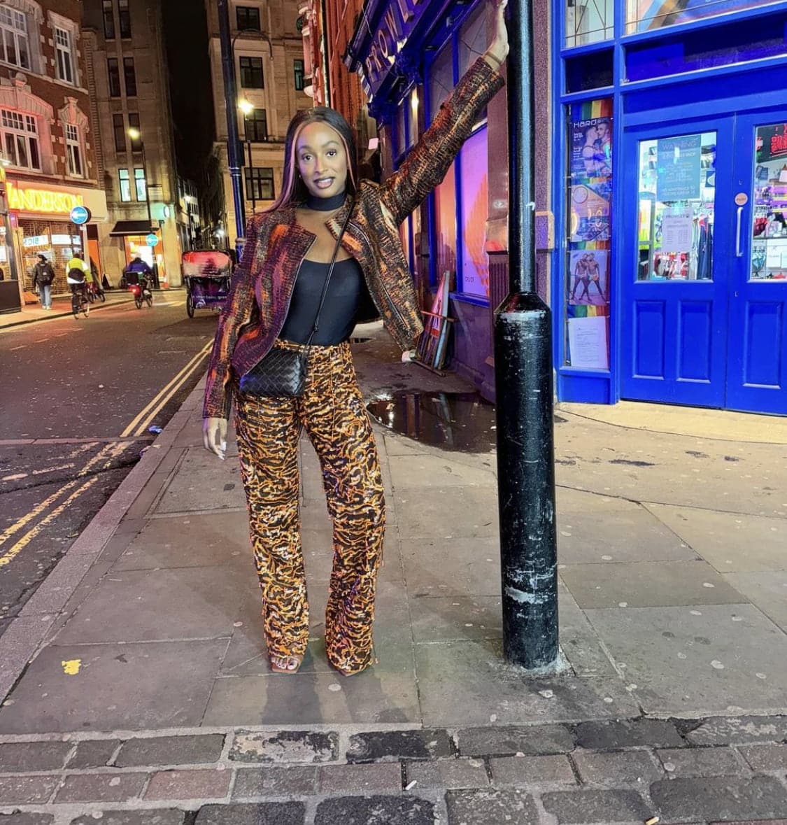 Dj Cuppy in an animal print leather jacket, paired with a black top, and striped leather pants.
